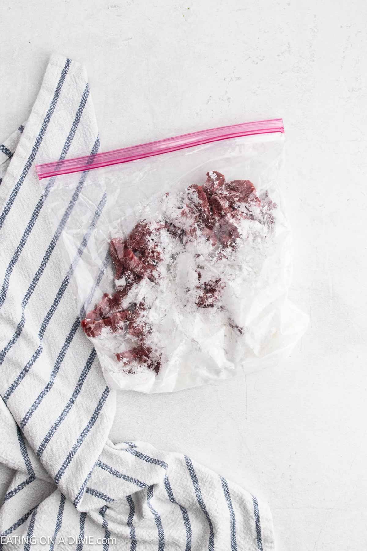 Flank steak strips in a zip lock bag with cornstarch.