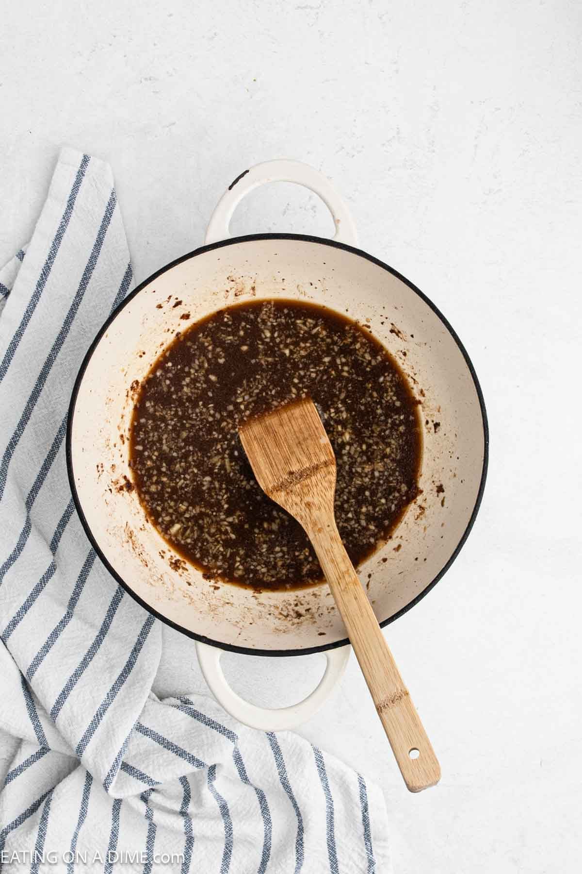 Stirring the gravy mixture in a Dutch oven with a wooden spoon.