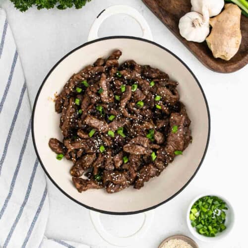 Beef Teriyaki topped with chopped green onions and sesame seeds in a large pot.