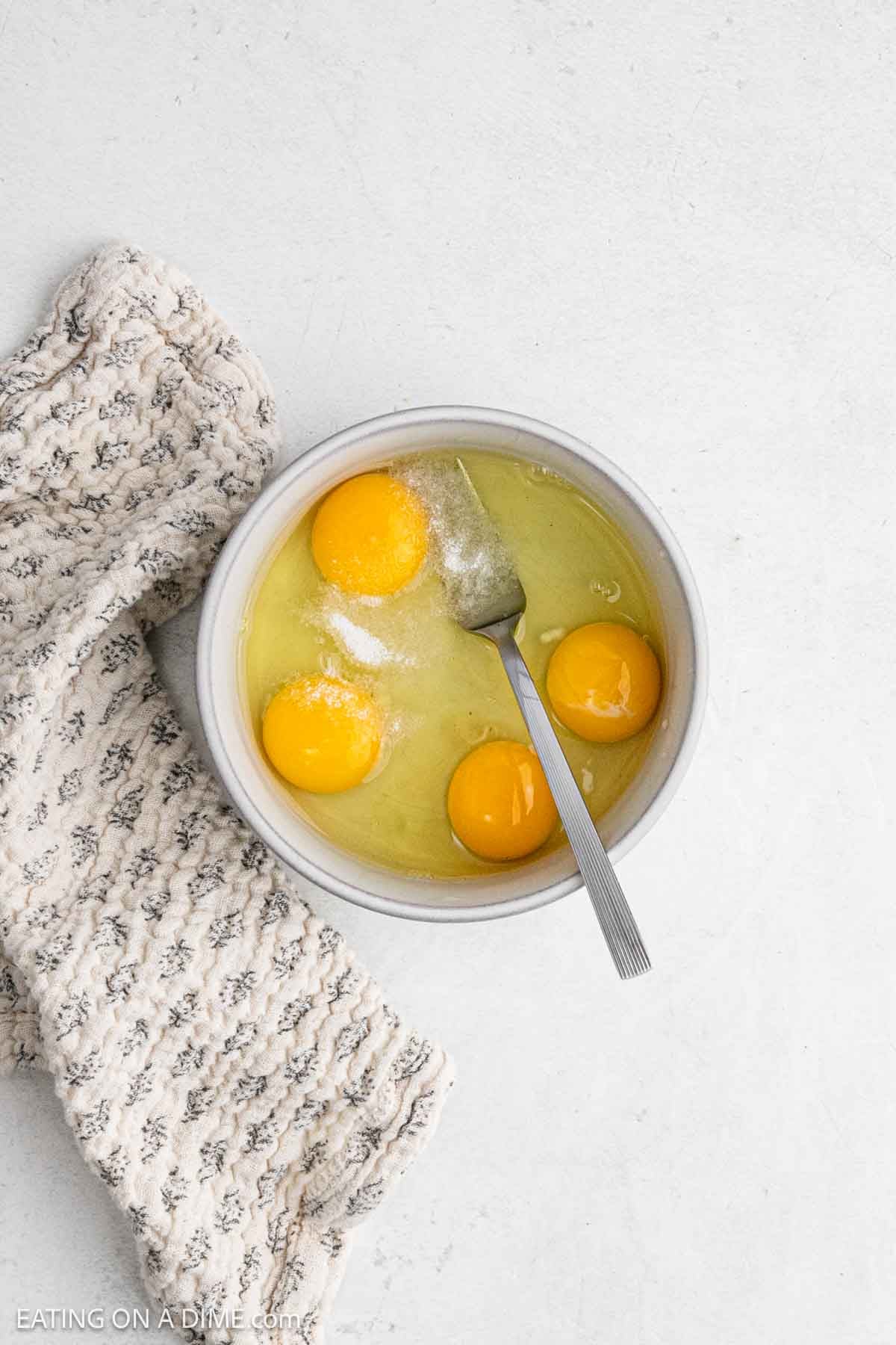 Whole eggs in a bowl topped with sea salt ready to be mixed with a fork.