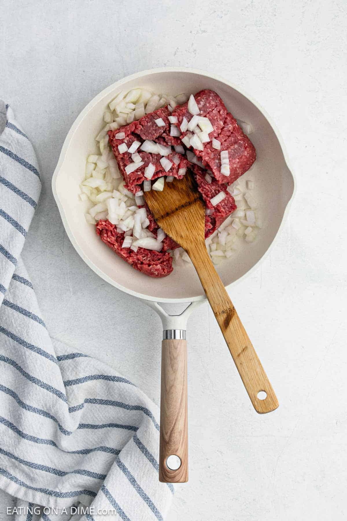 Ground beef in a skillet with chopped onions.