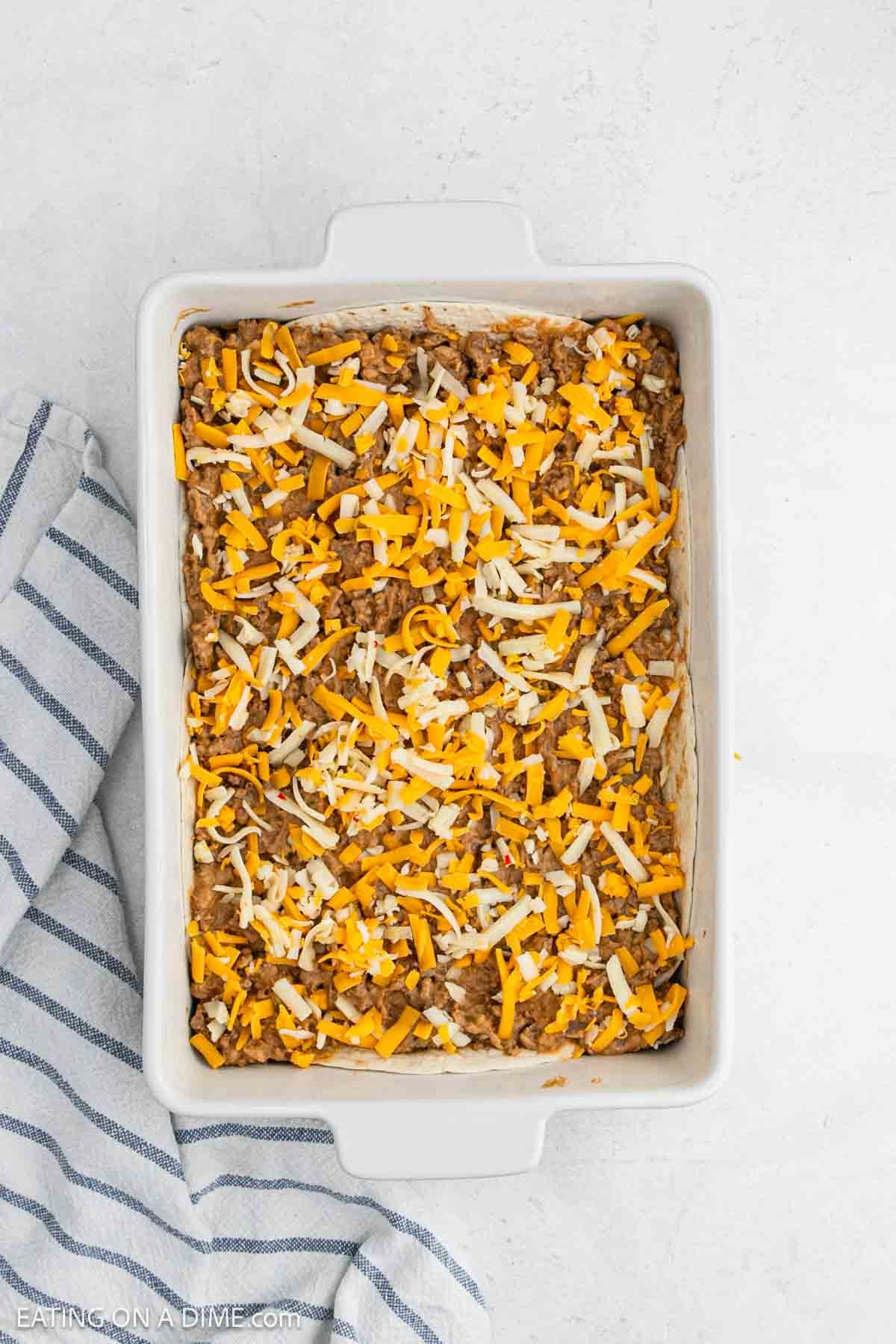 Meat mixture topped with shredded cheese in a baking dish.