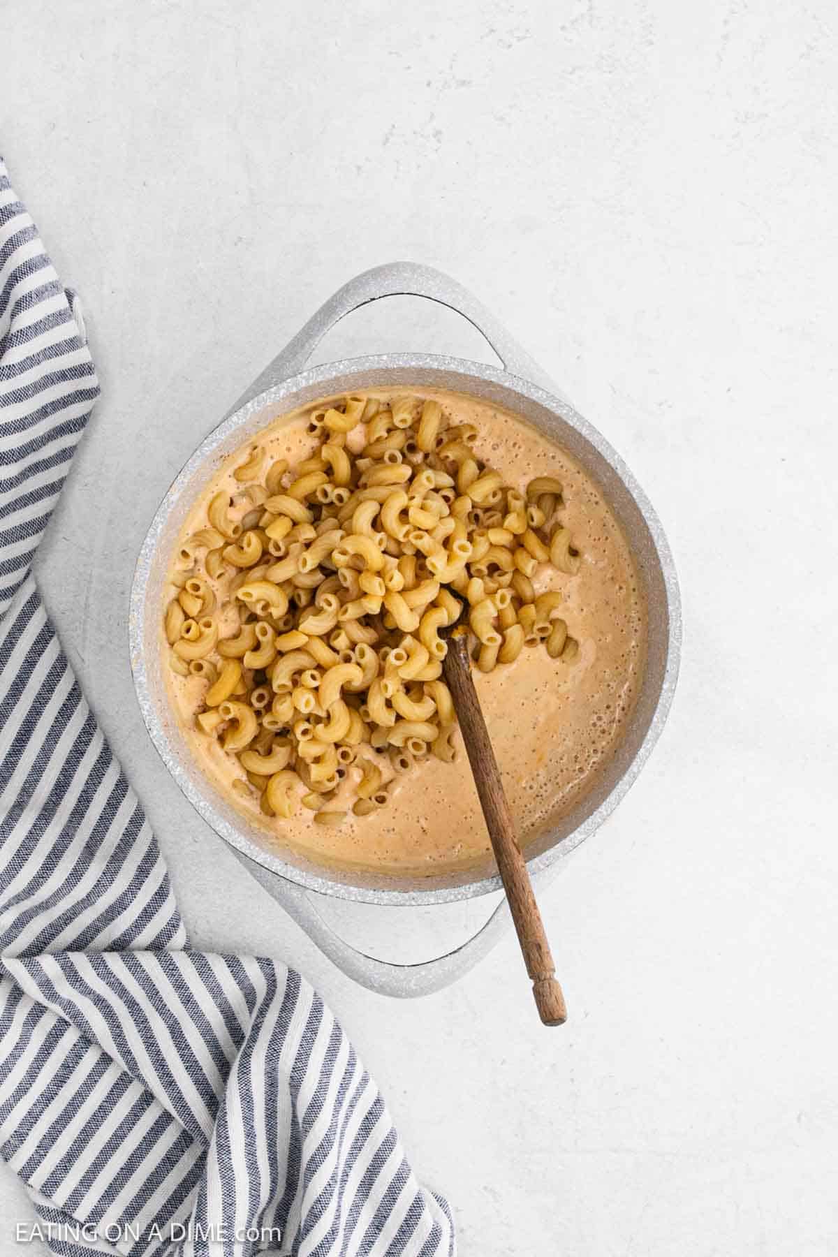 Macaroni noodles added to the cheese mixture in a large pot.