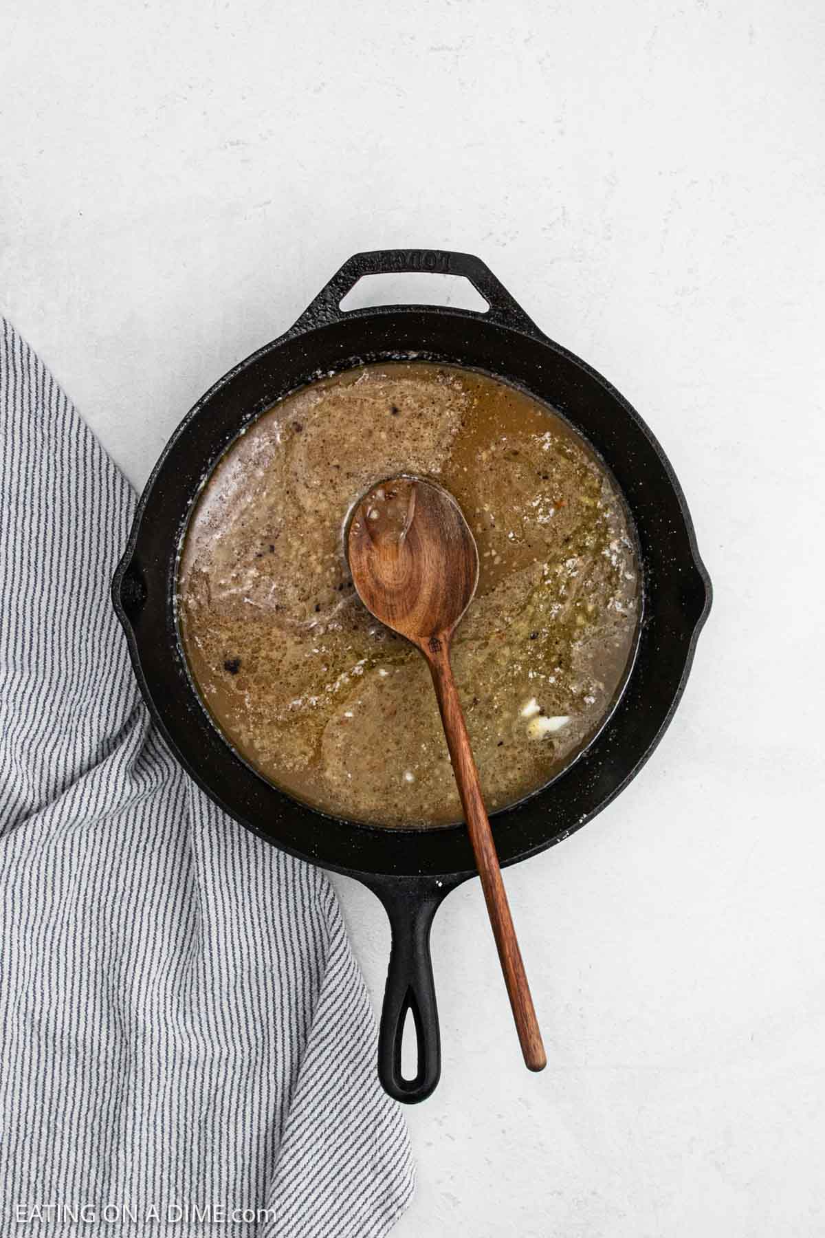 Mixing the sauce mixture in a cast iron skillet with a wooden spoon.