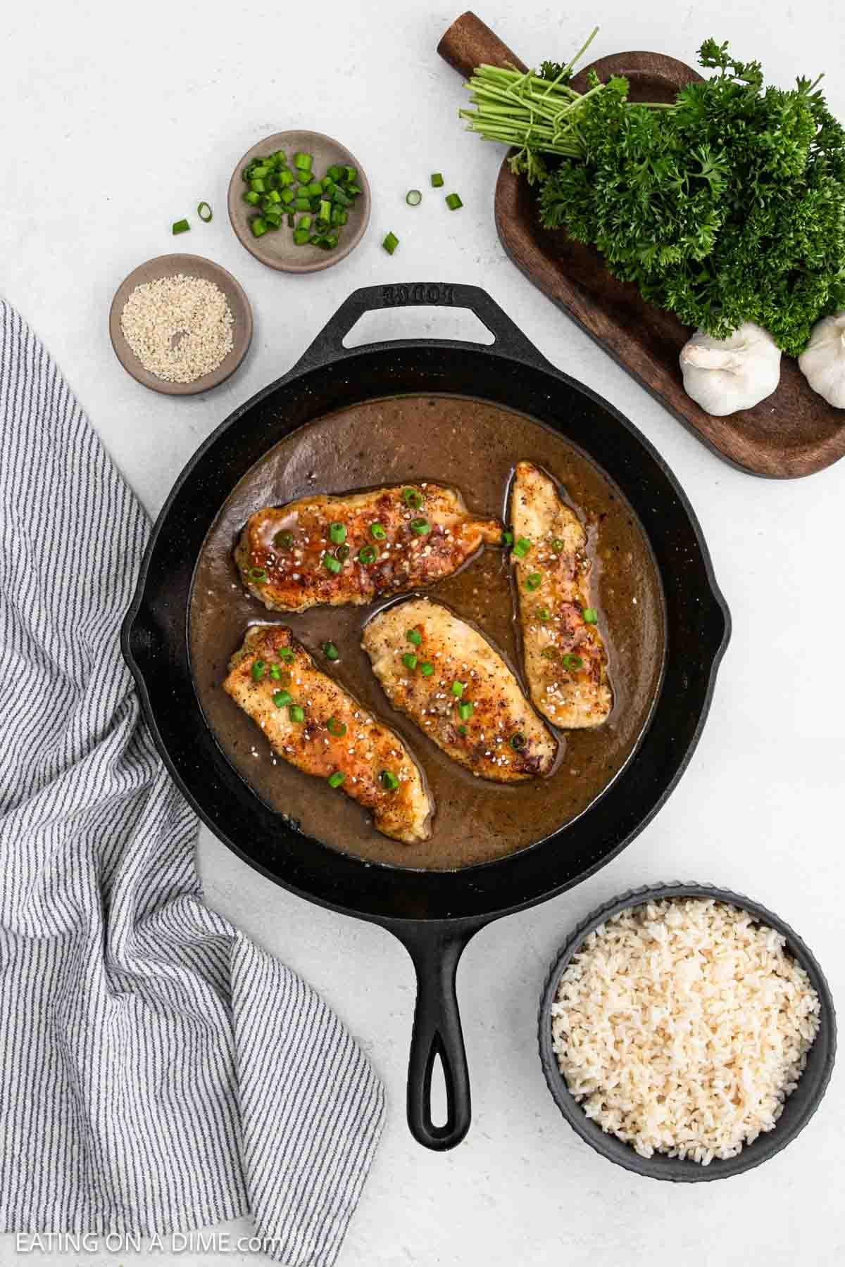 Chicken breast in a cast iron skillet covered with gravy.