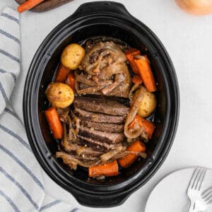 Sliced london broil in the slow cooker with a side of potatoes and carrots.