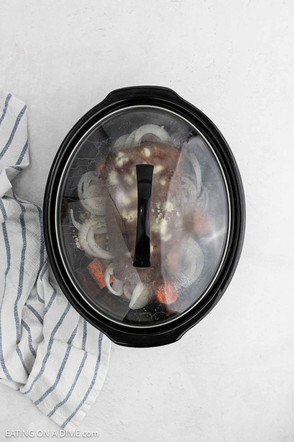 Placing the lid on the crockpot with the ingredients inside to slow cook.