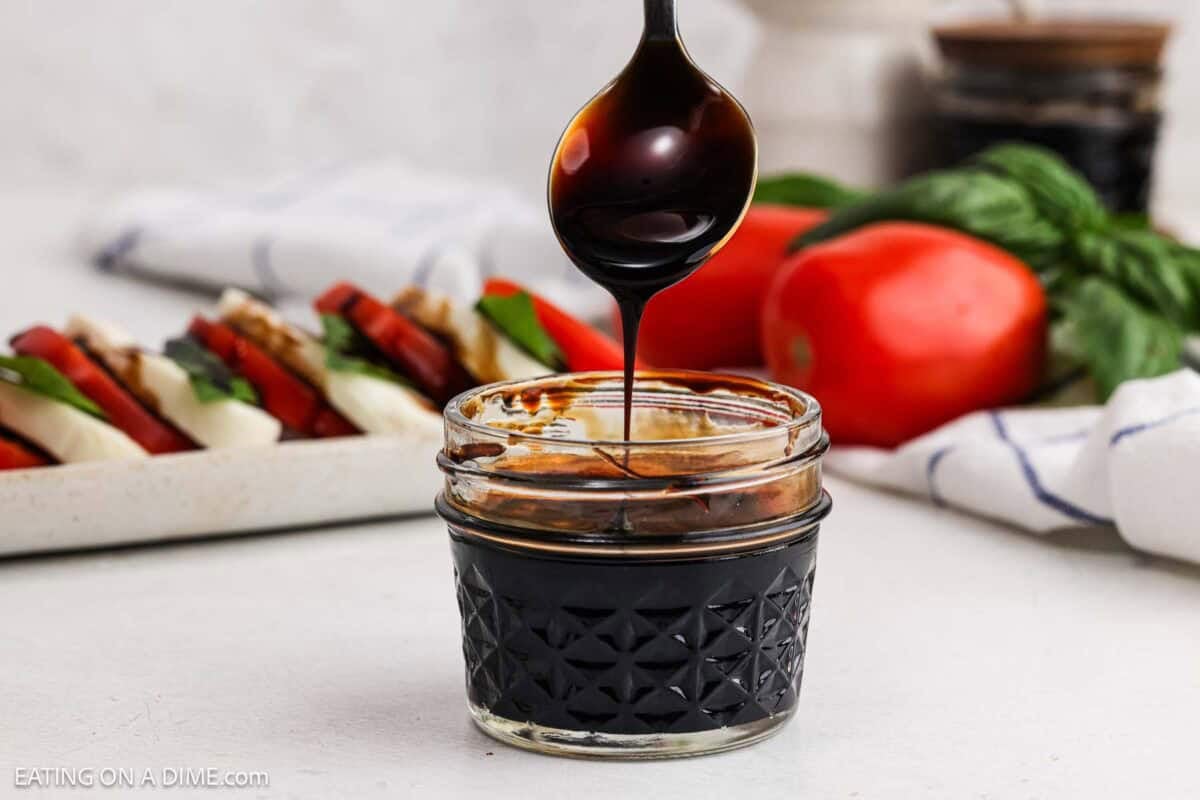 Balsamic glaze in a small jar with a serving on the spoon.