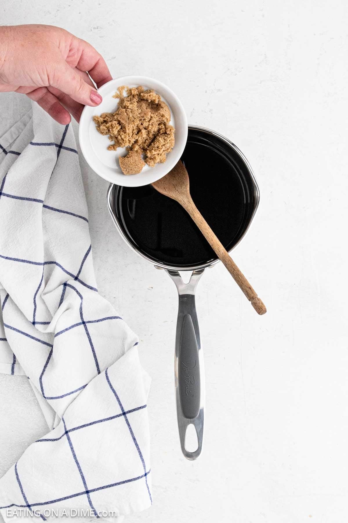 Pouring brown sugar into the saucepan with the balsamic vinegar.