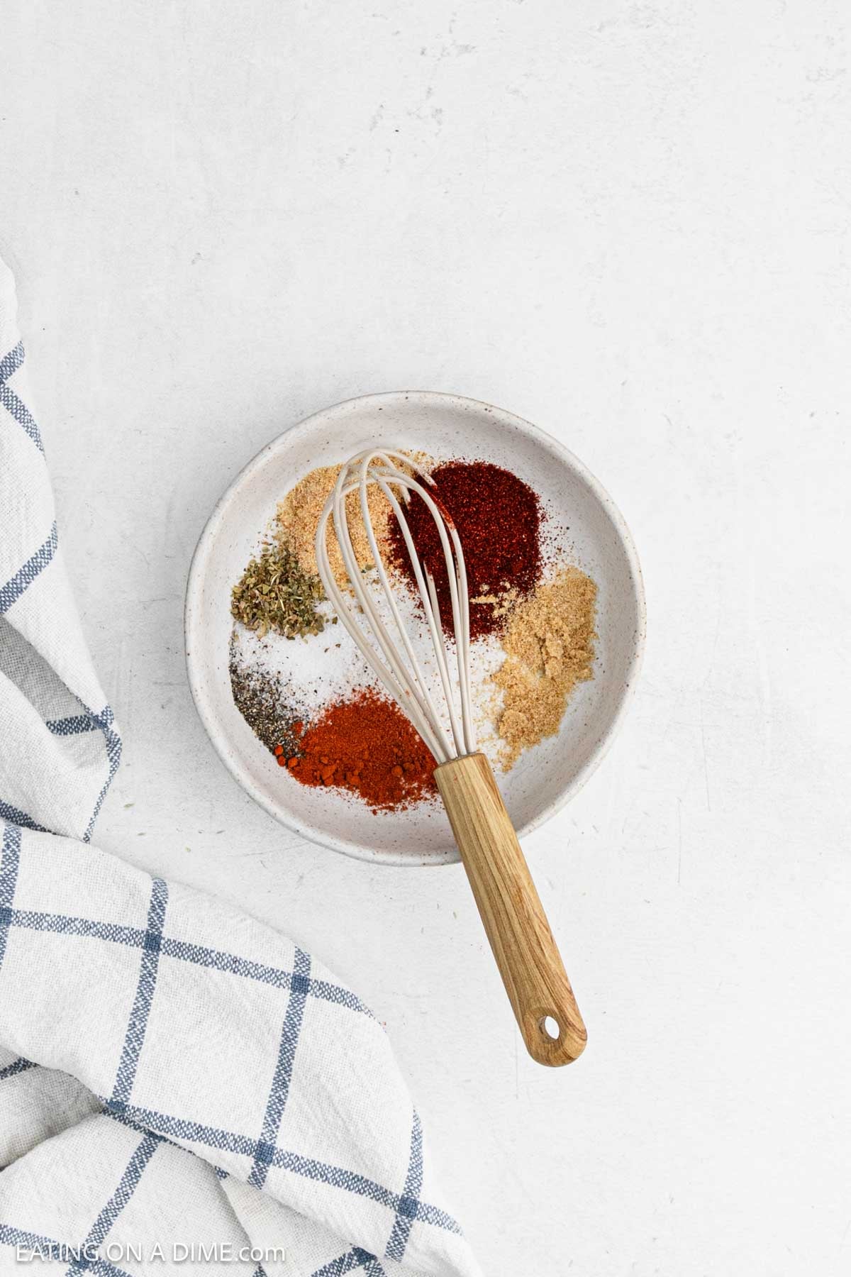 Spices placed in a bowl with a whisk on top.