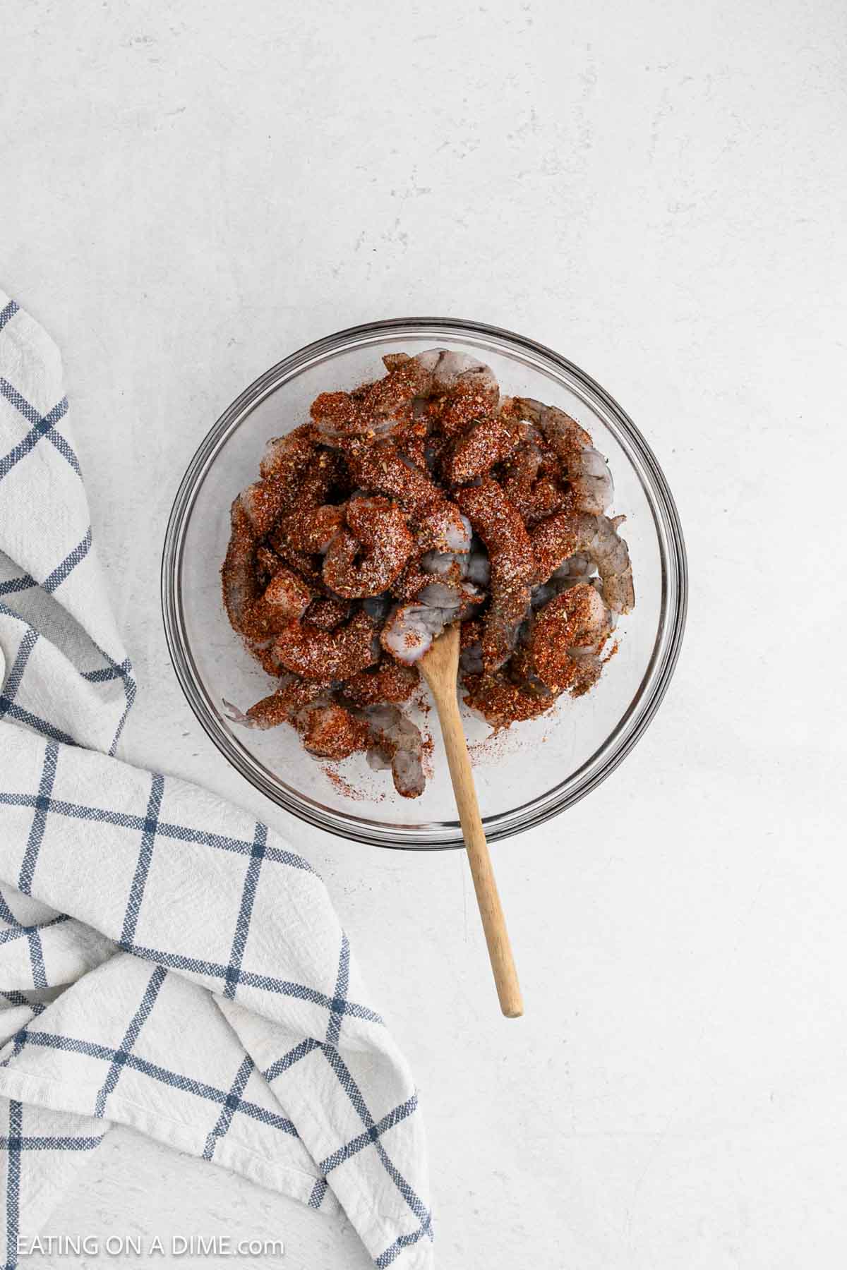 Mixing the raw shrimp with the spice blend in a bowl.