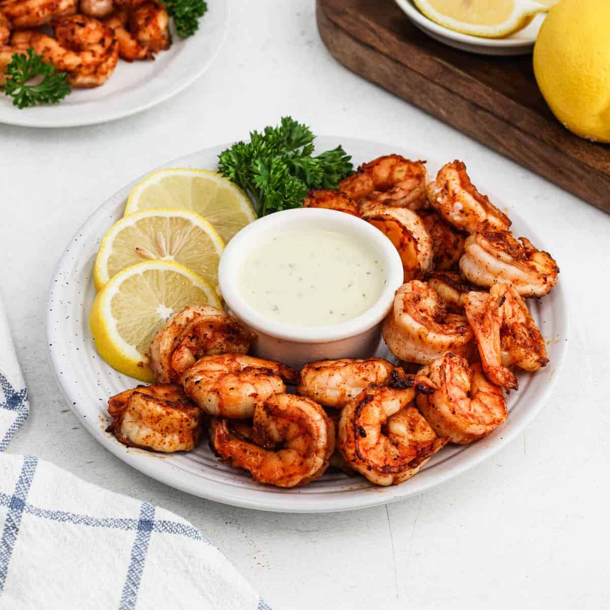 Blackened Shrimp stacked on a platter with a bowl of sauce in the center of the platter.
