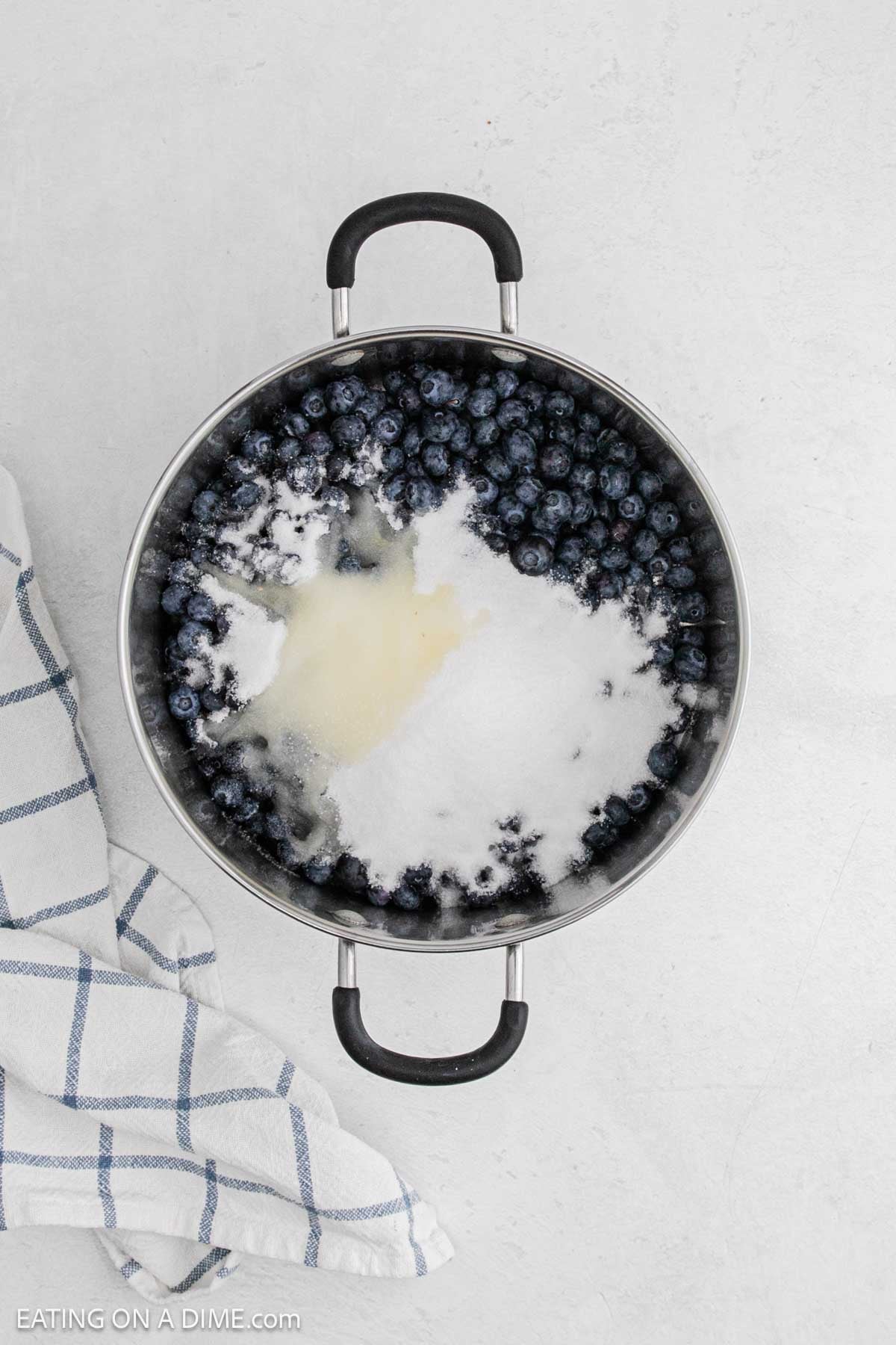 Blueberries in a large pot topped with sugar and lemon juice.