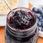 Blueberry Jam in a jar with a serving on a spoon.