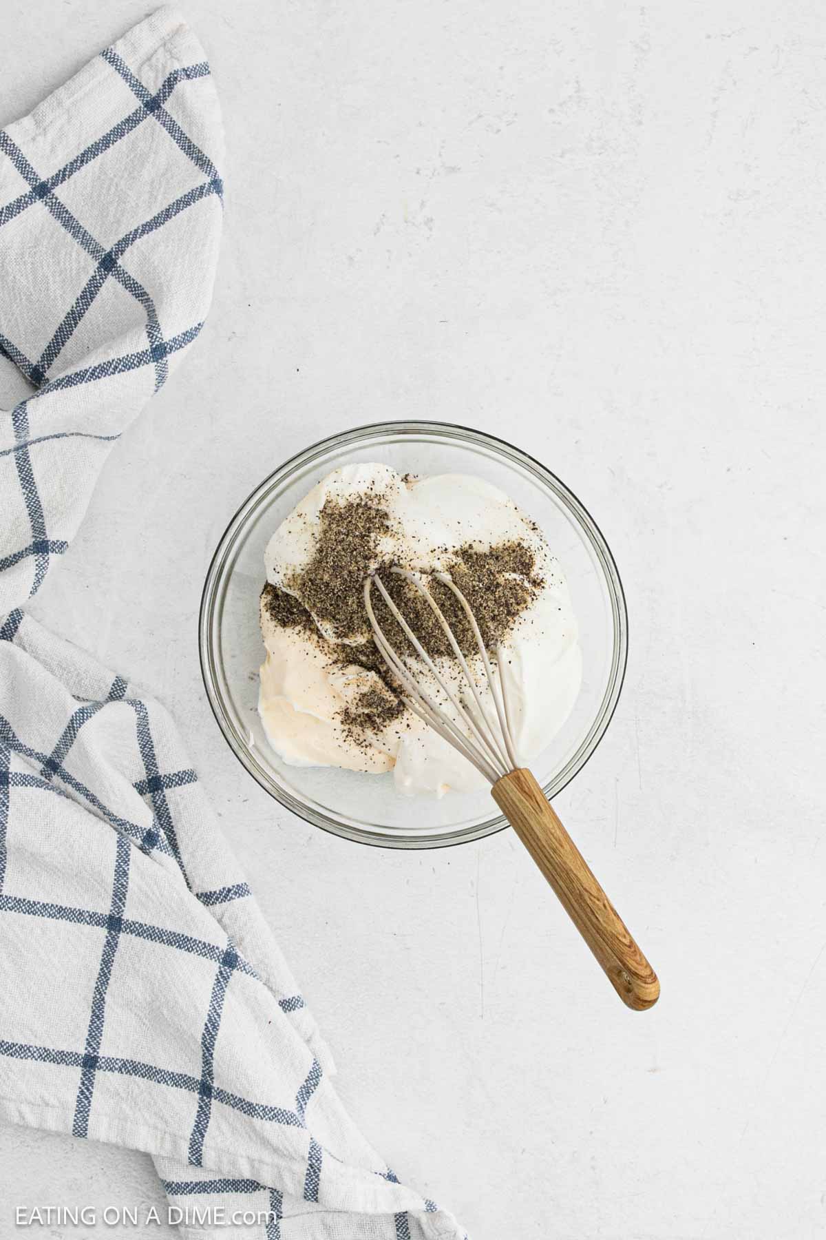 Combining the dressing ingredients in a bowl with a whisk.