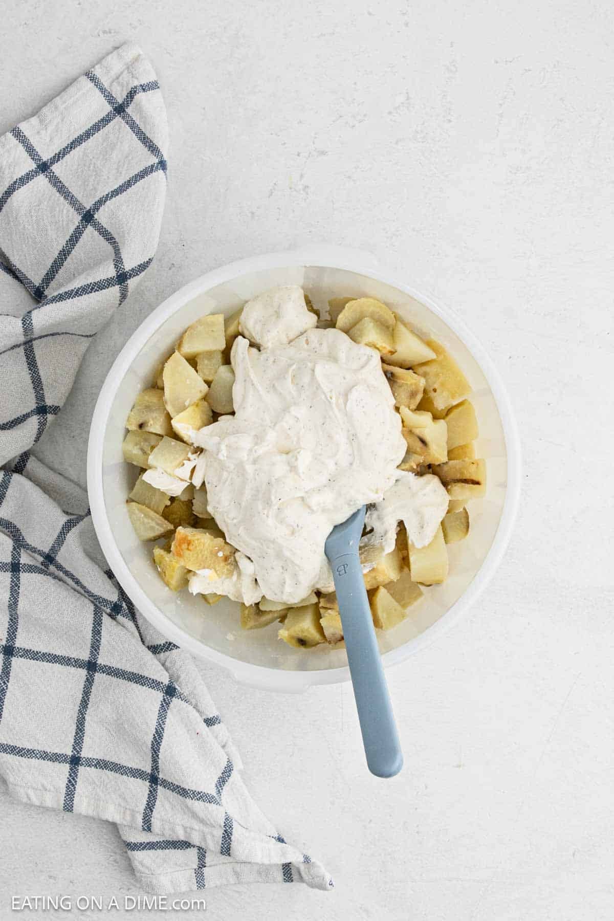 Dressing topped the diced baked potato in a bowl.