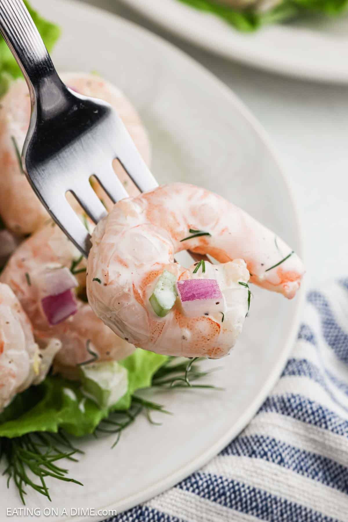 Close up image of shrimp on a fork coated with dressing.