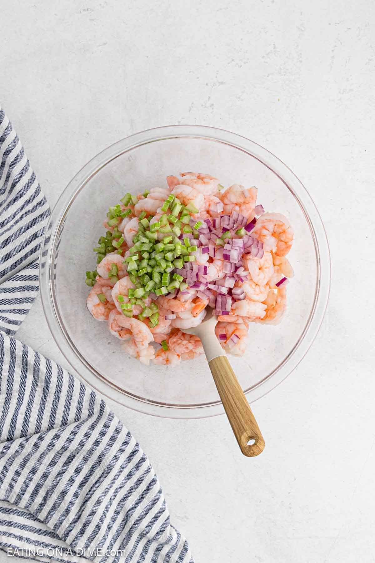 Coating the cooked shrimp with the dressing.