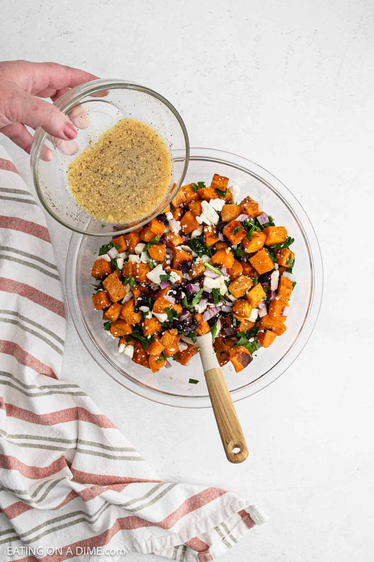 Pouring the dressing over the sweet potato mixture in a bowl.