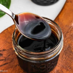 Balsamic glaze in a clear jar with a serving on a spoon.