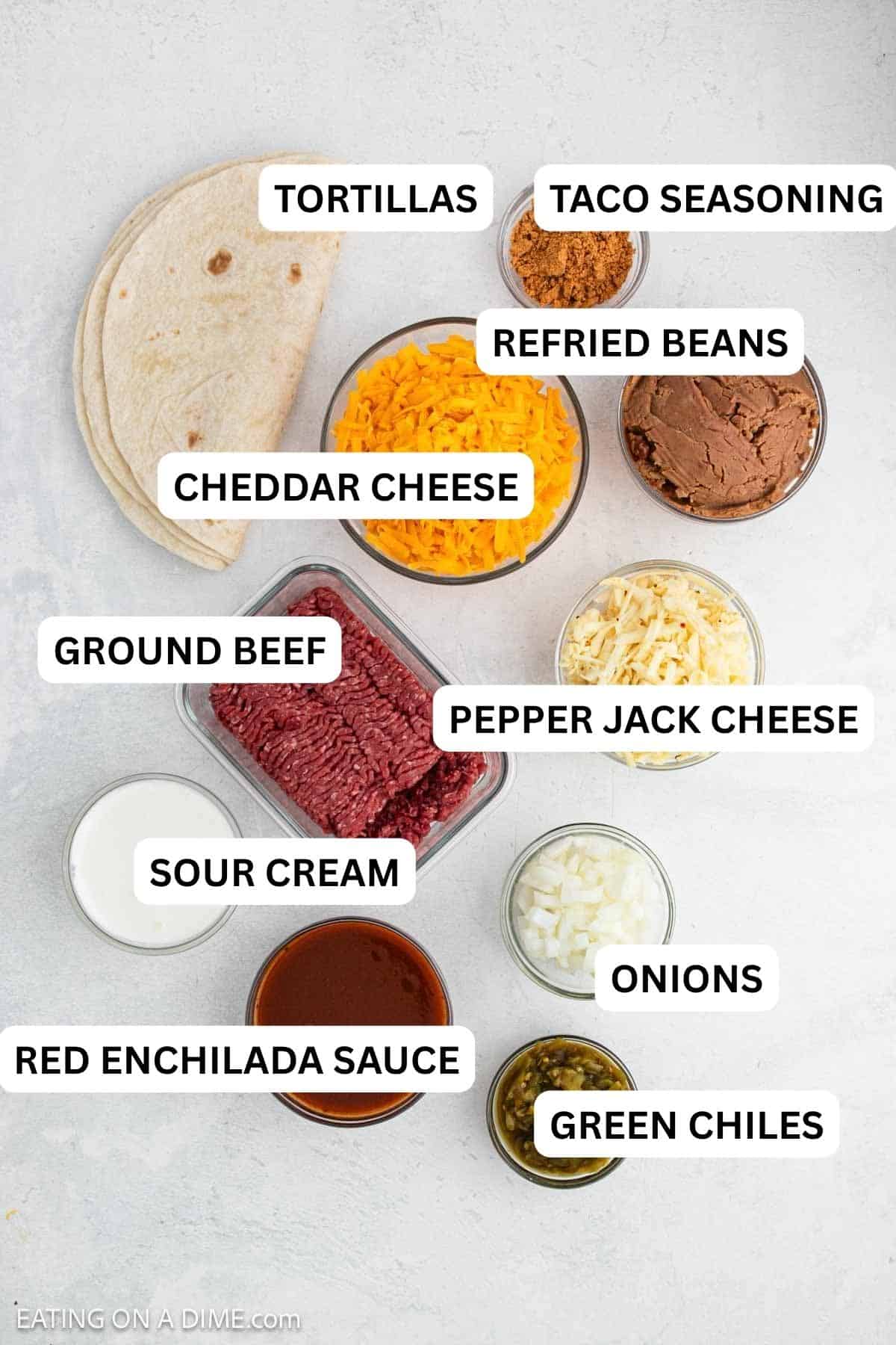 Ingredients needed for this recipe includes ground beef, onion, diced green chiles, taco seasoning, refried beans, sour cream, flour tortillas, red enchilada sauce, and cheese.