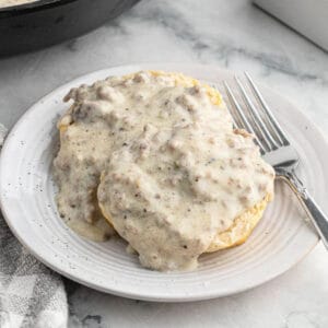 Gravy served over biscuits on a white plate.