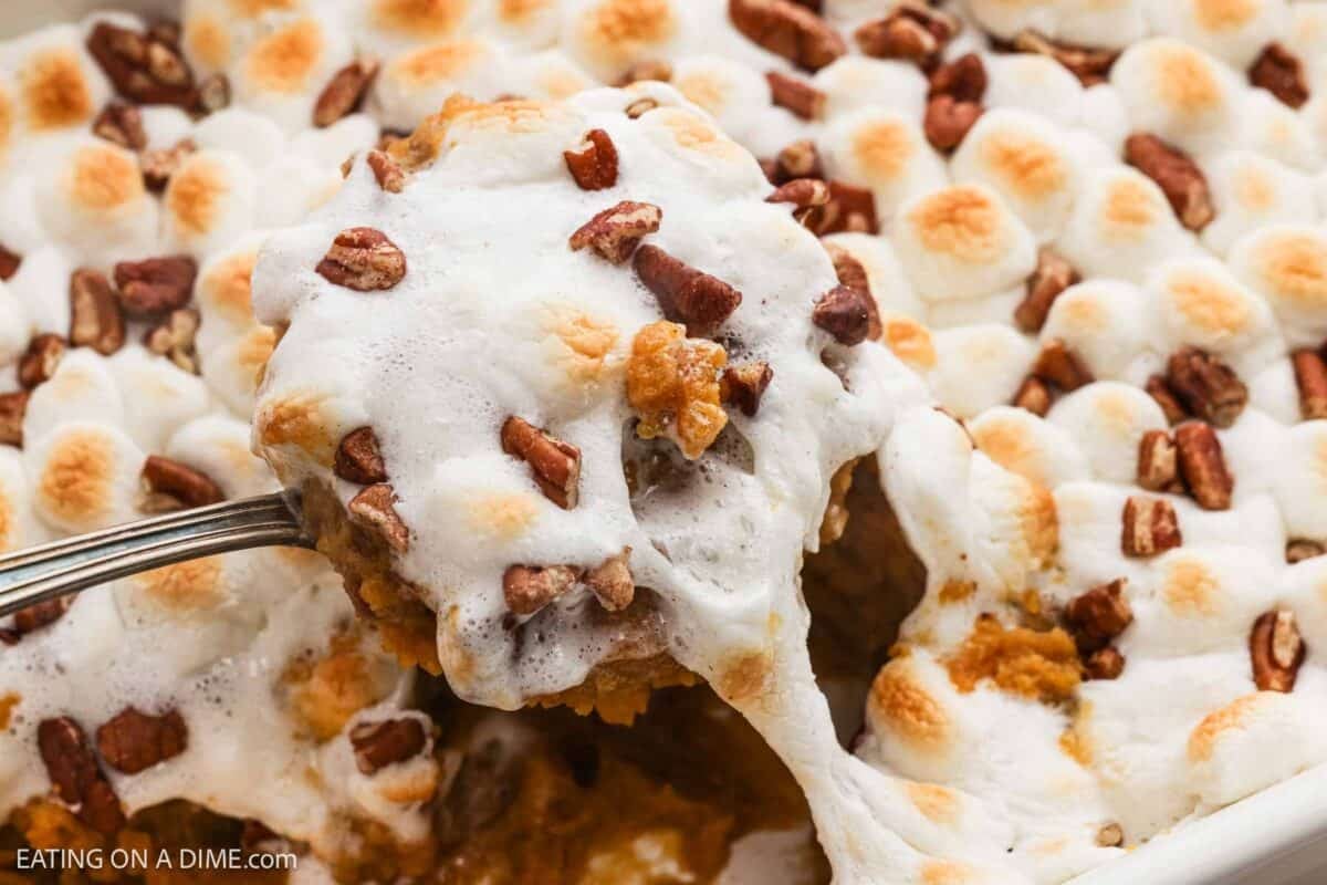 Canned sweet potato casserole in a baking dish with a serving on a spoon.