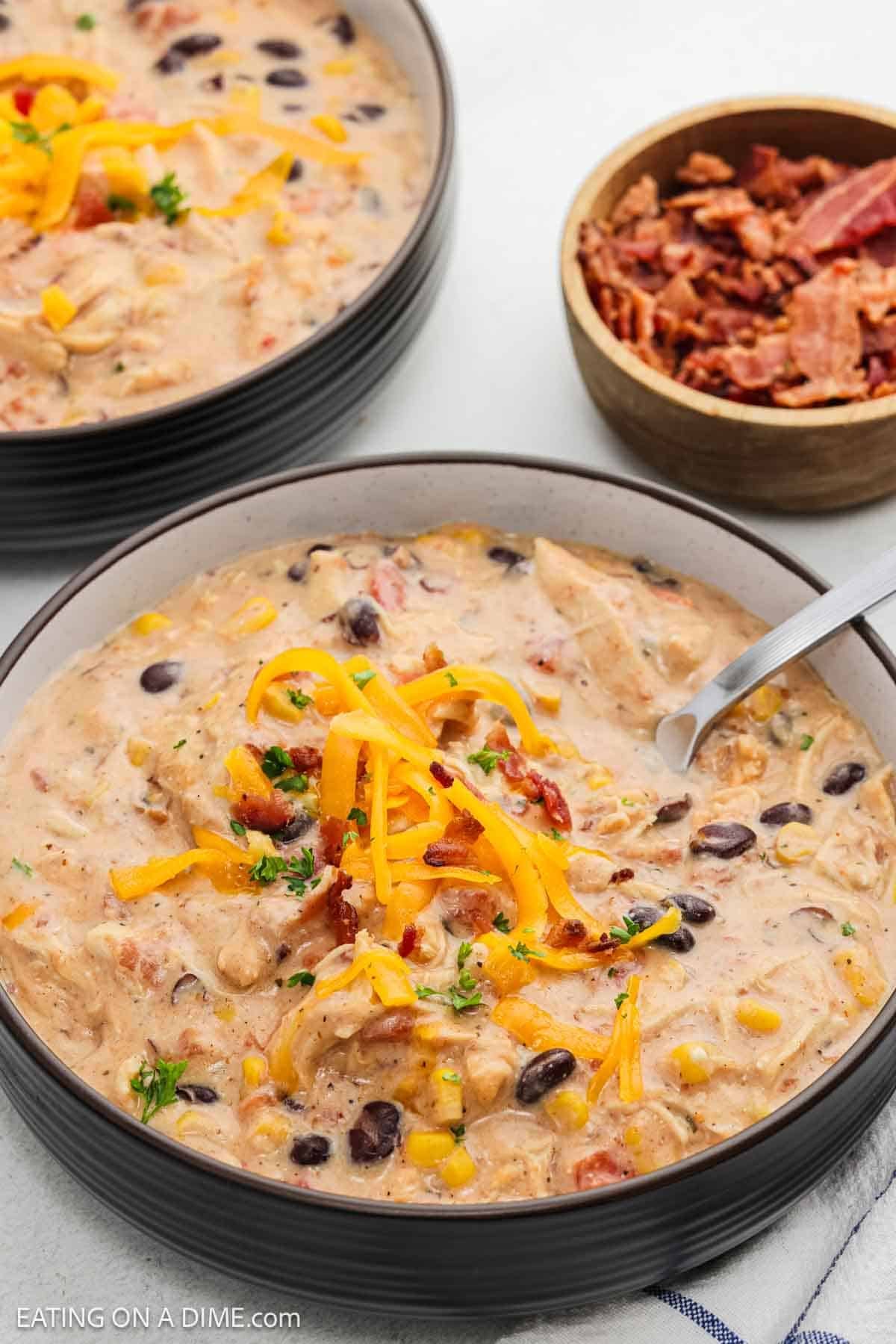Creamy chicken chili in a bowl topped with shredded cheese.