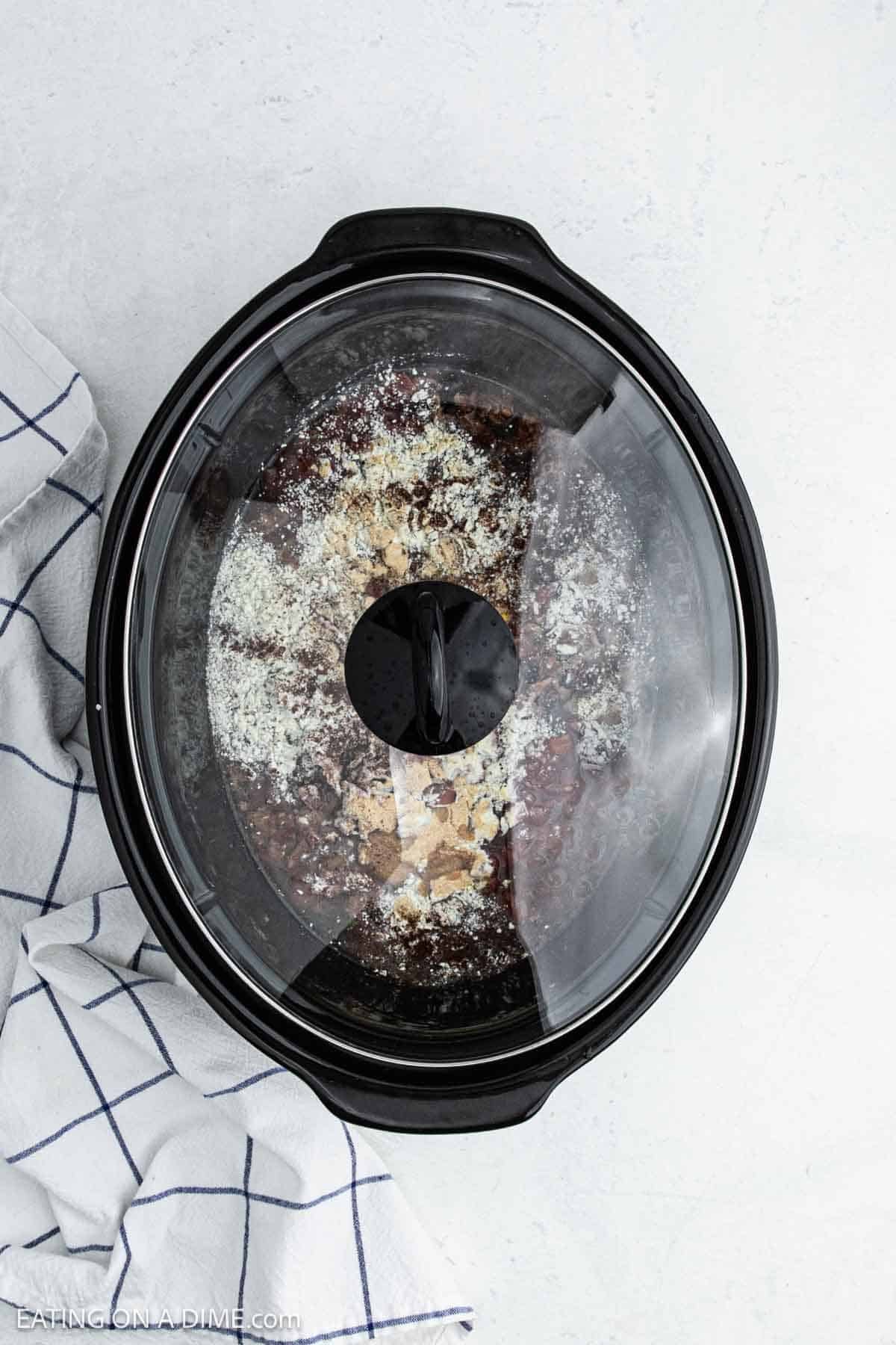 Ingredients added to the slow cooker topped with the lid.