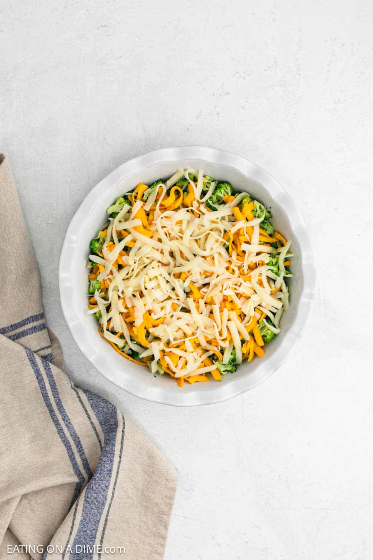 Shredded cheese topped the cooked broccoli in a pie plate.