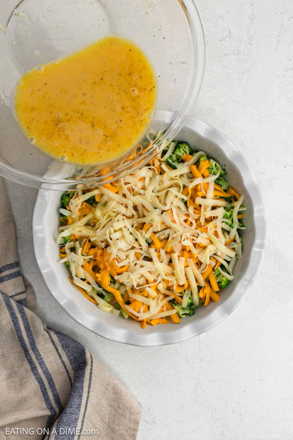 Pouring egg mixture into the pie plate with the shredded cheese and broccoli.