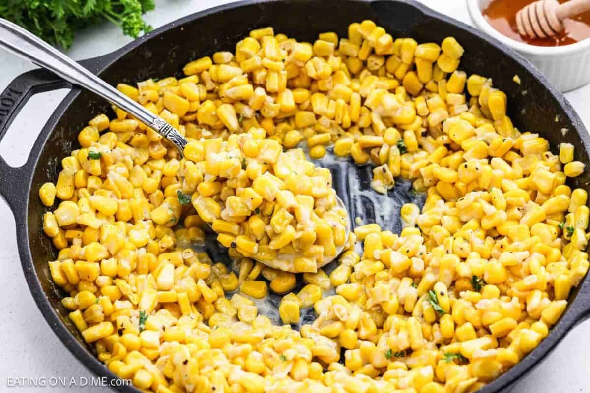 Honey butter skillet corn in a cast iron skillet with a serving on a spoon.