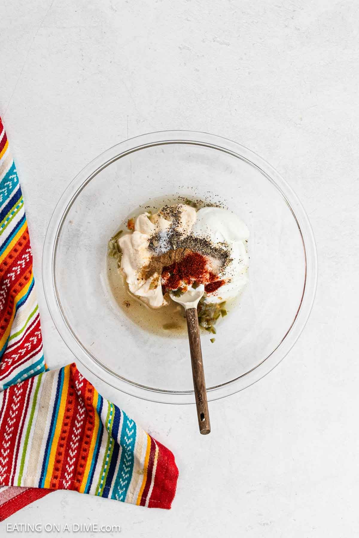 Combining the dressing ingredients together in a bowl with a wooden spoon.