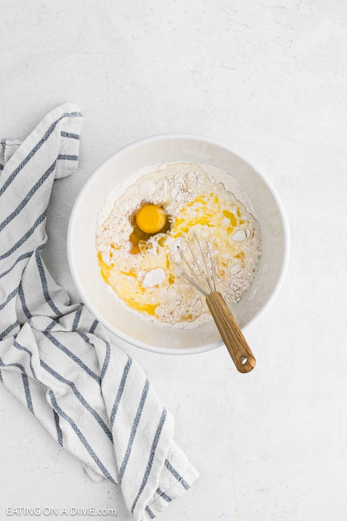 Combining the dry ingredients with egg and milk in a bowl with a whisk.