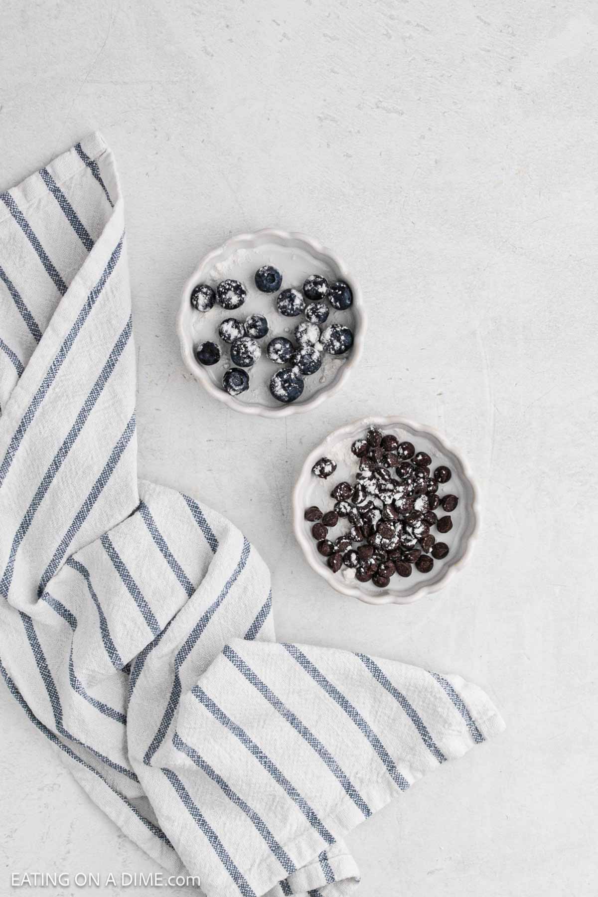 Blueberries and chocolate chips in a bowl covered with flour.