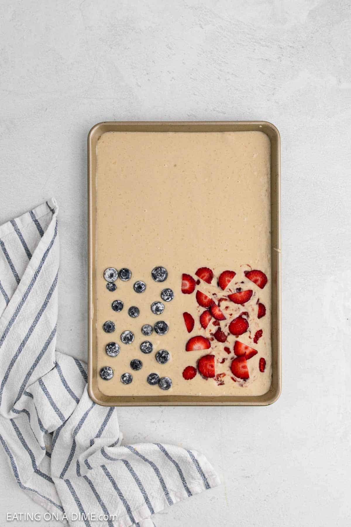 Topping the batter with blueberries and strawberries in the pan.