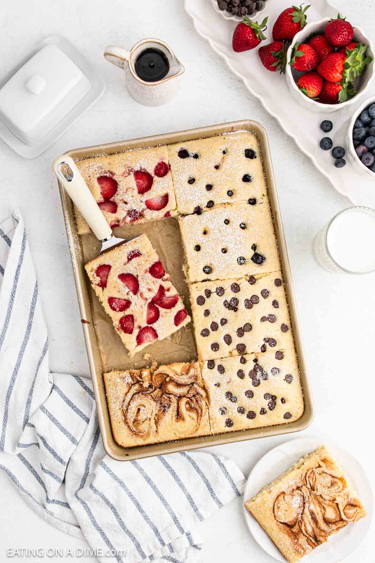 Baked pancakes in a pan topped with chocolate chips, cinnamon, strawberries and blueberries.