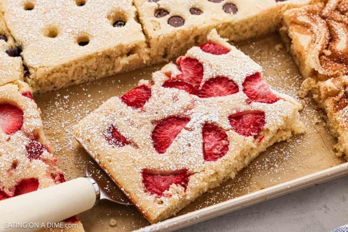 Close up image of sheet pan pancakes topped with strawberries and chocolate chips.