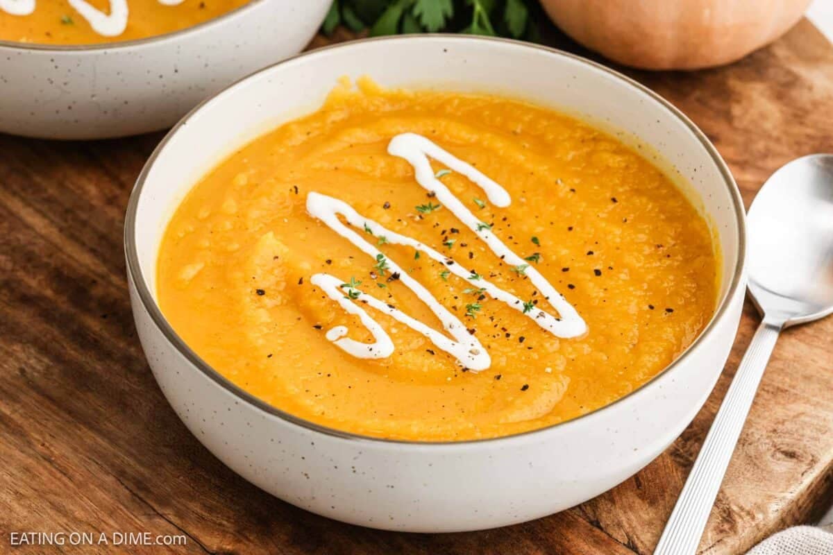 A bowl of Butternut squash soup and topped with a drizzle of heavy cream.