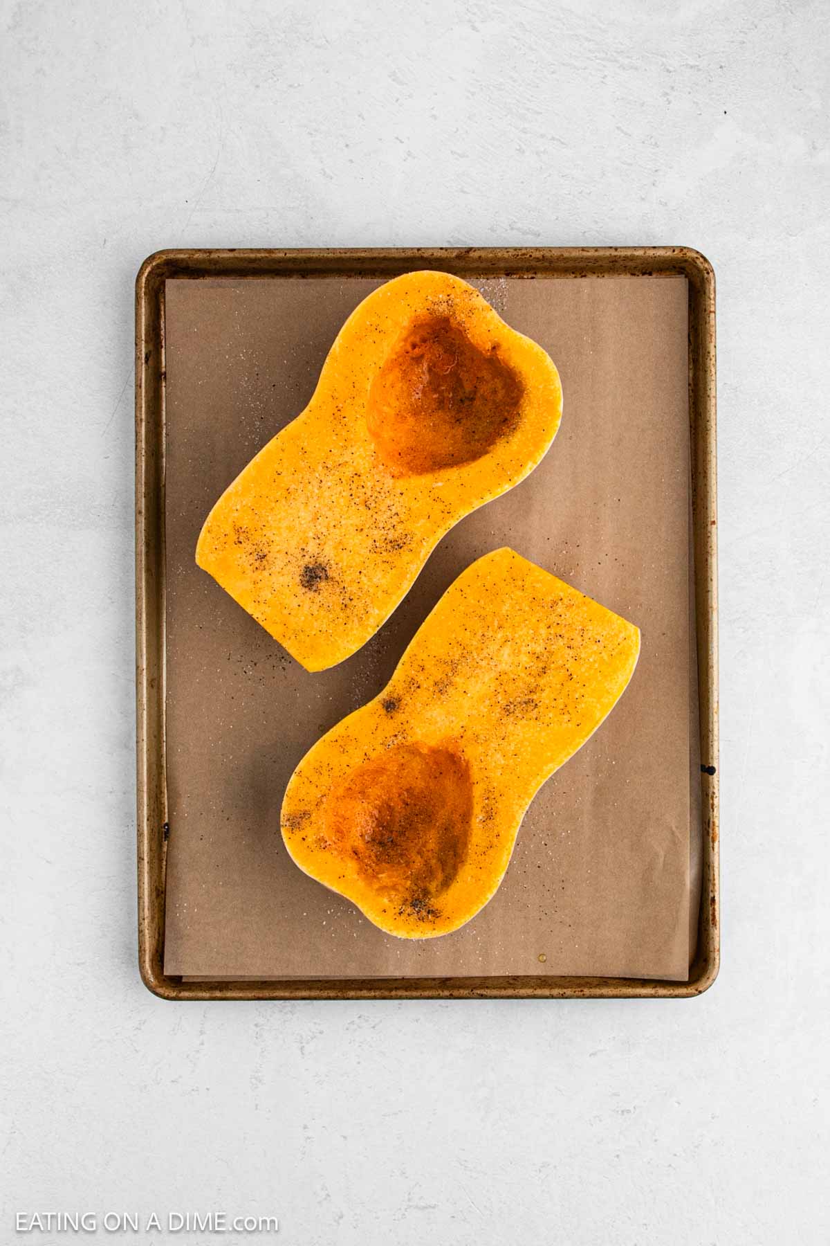Seasoned and roasted butternut squash on a baking sheet.