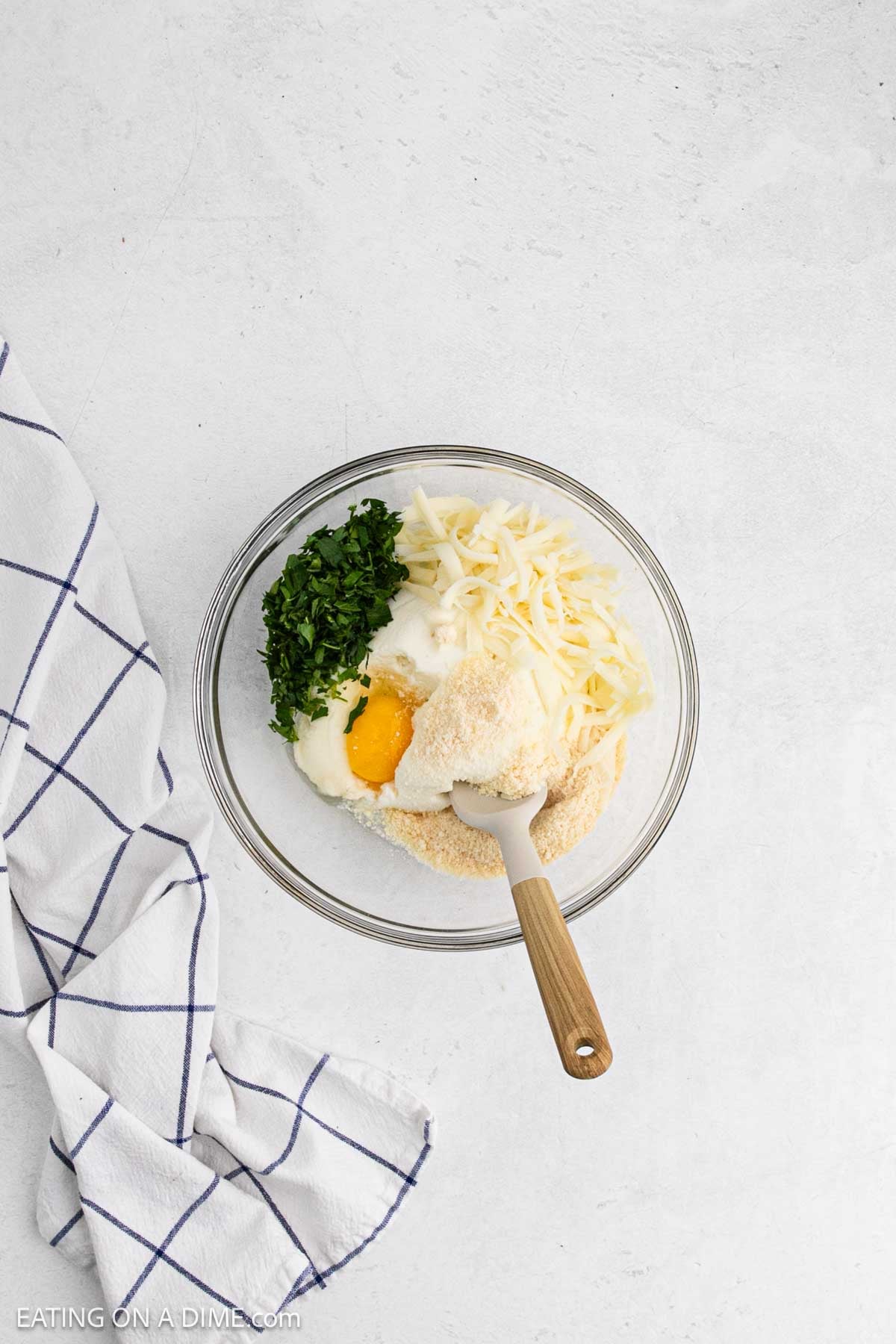Ricotta cheese, egg, parmesan, parsley and mozzarella cheese in a bowl.