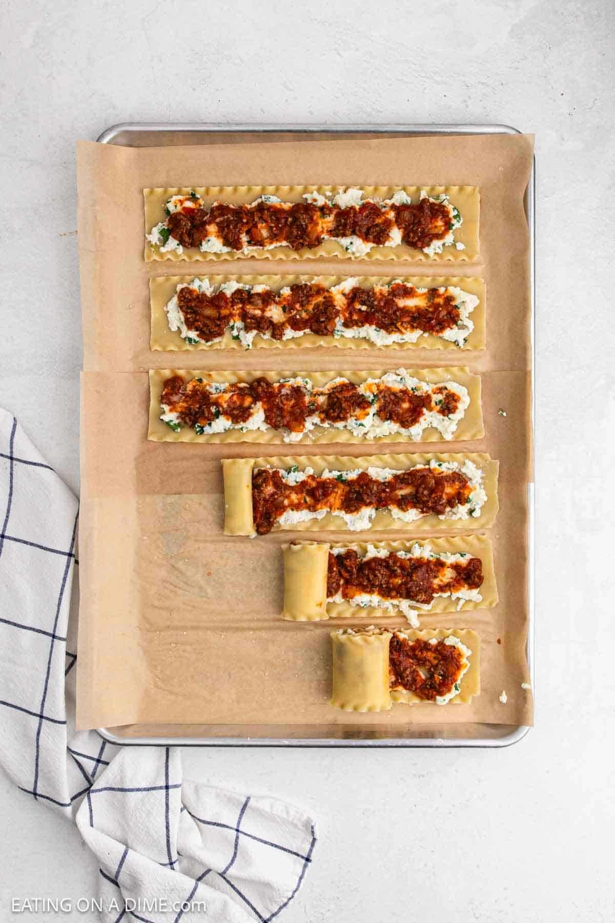 Meat sauce added to the lasagna noodles topped with the ricotta mixture on a baking sheet.