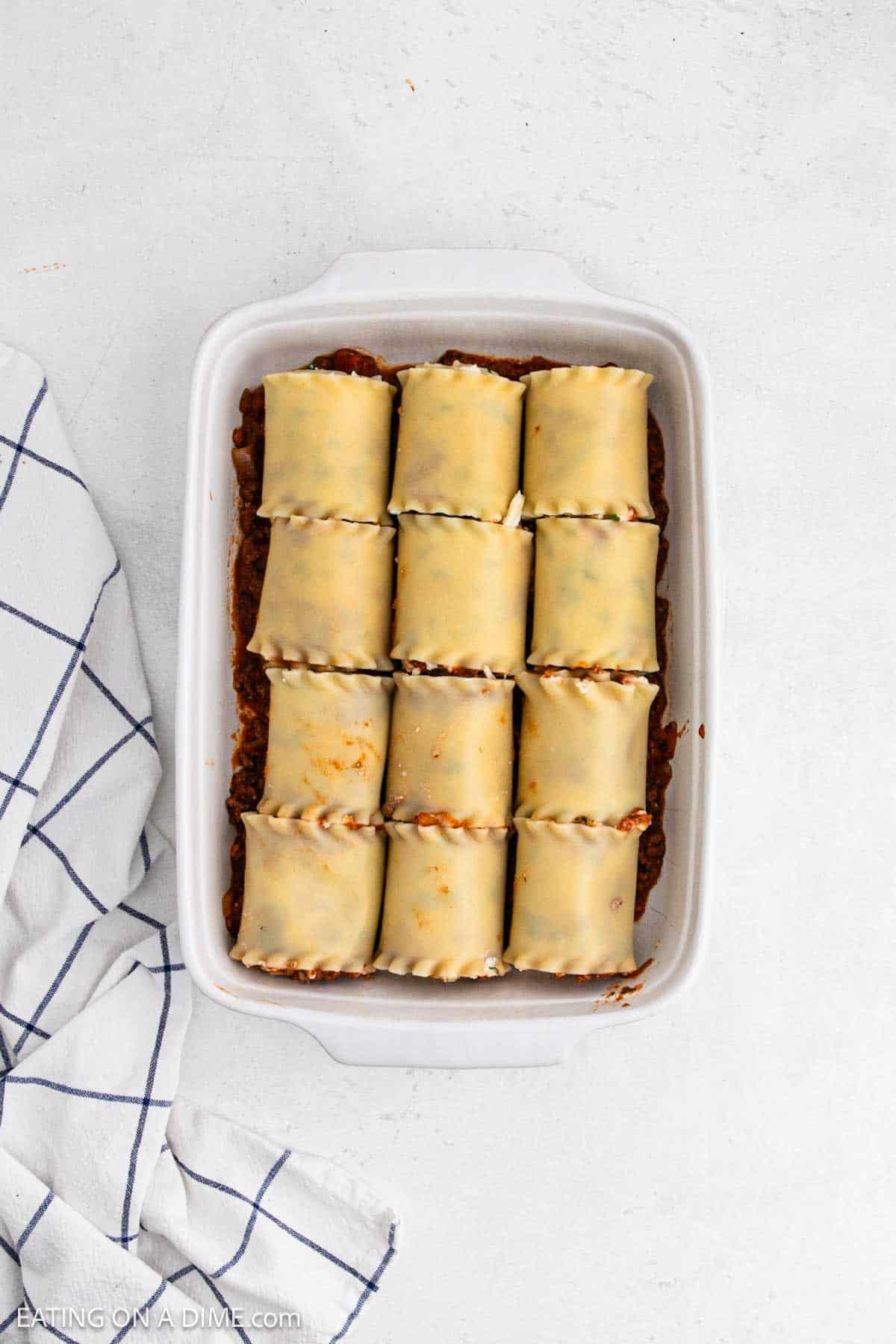 Rolled lasagna noodles placed in a baking dish.