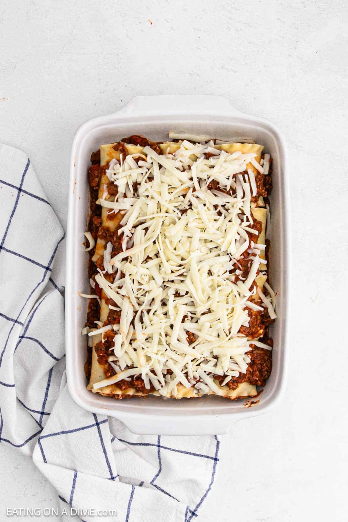 Shredded cheese topped the meat sauce and rolled lasagna noodles in the baking dish.