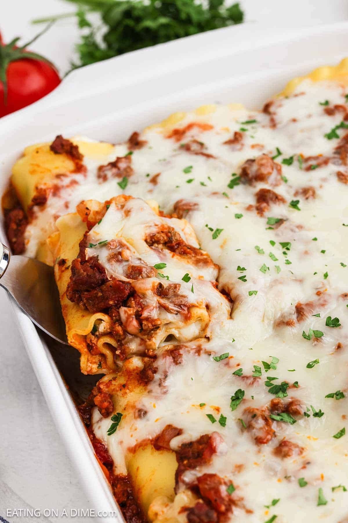 Rolled lasagna covered with meat sauce and melted cheese in a baking dish ready to serve.