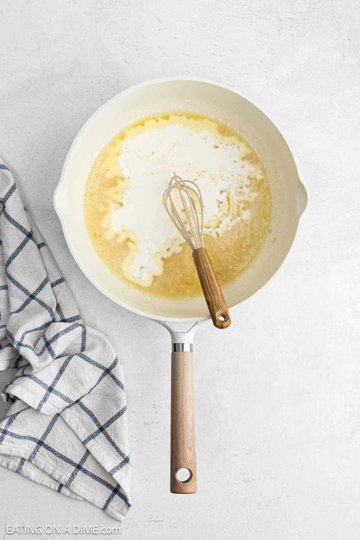 Whisking cream and milk in a large skillet mixed with melted butter.