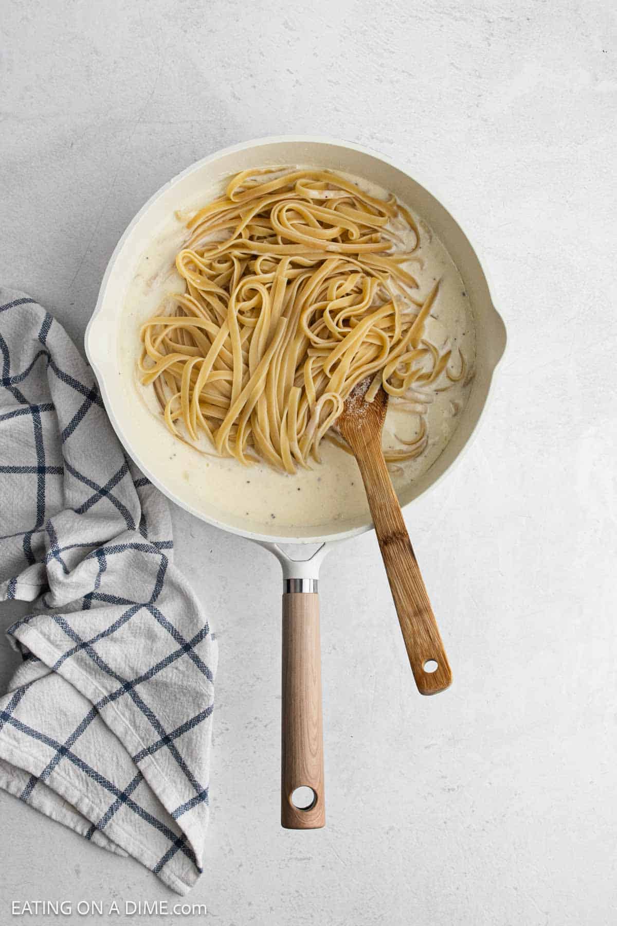 Cooked pasta is added to the creamy mixture in a skillet.