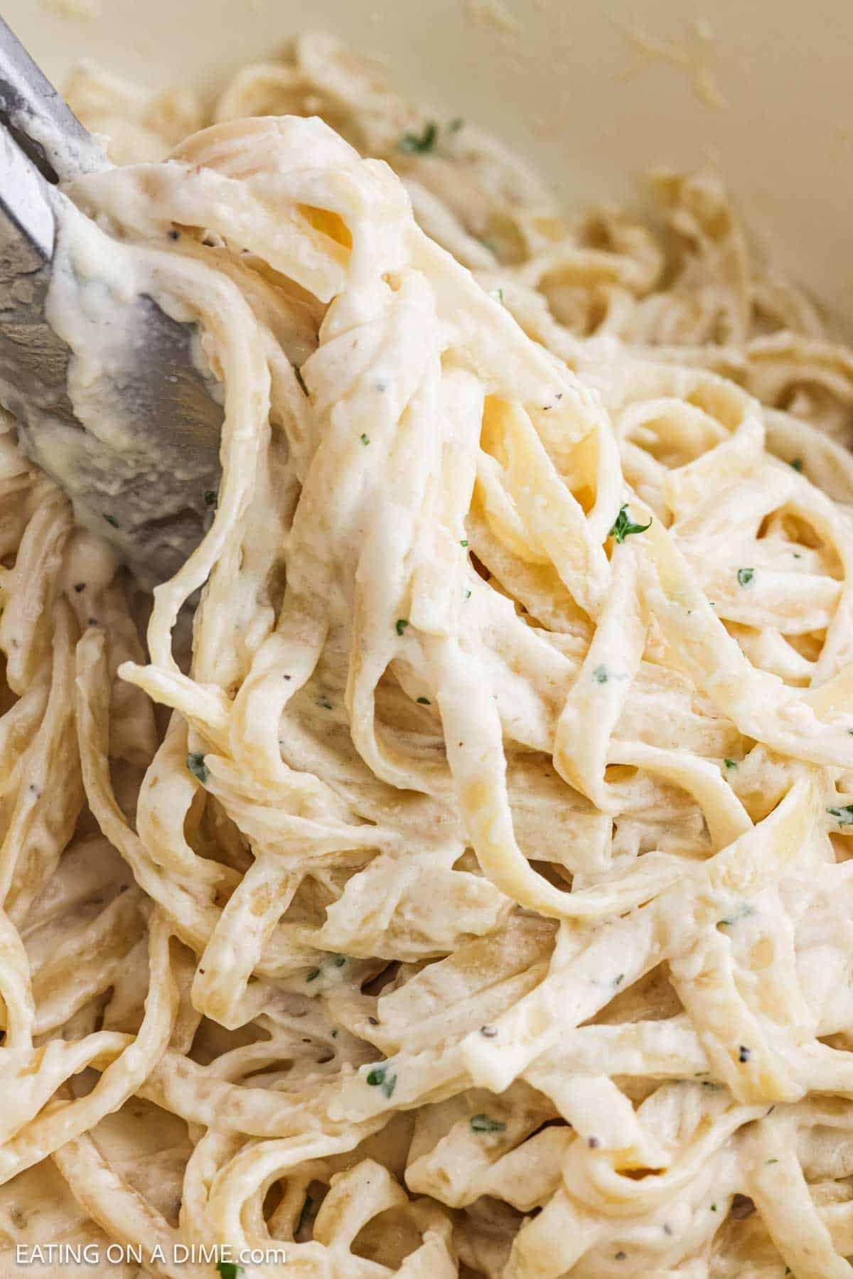 Close up image of fettuccine pasta mixed in a creamy sauce.