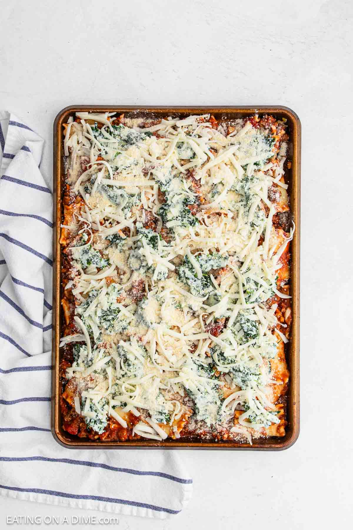 Shredded cheese, parmesan cheese spread over the lasagna mixture.