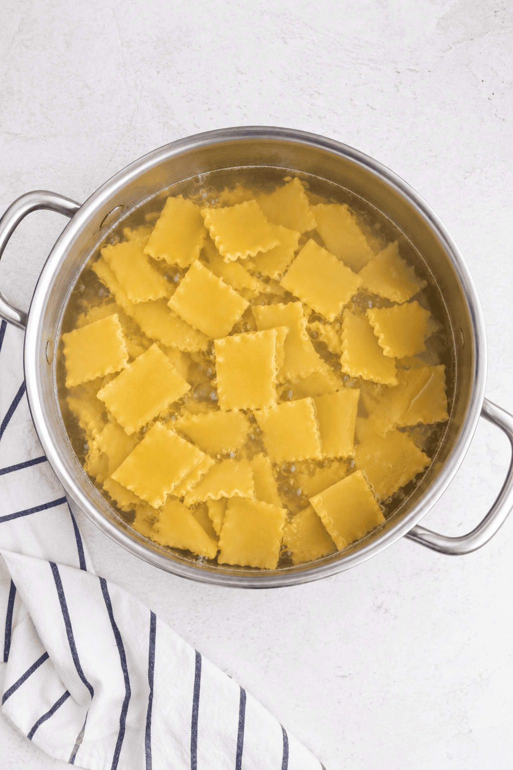 Broken lasagna noodle cooking in a large pot of water.